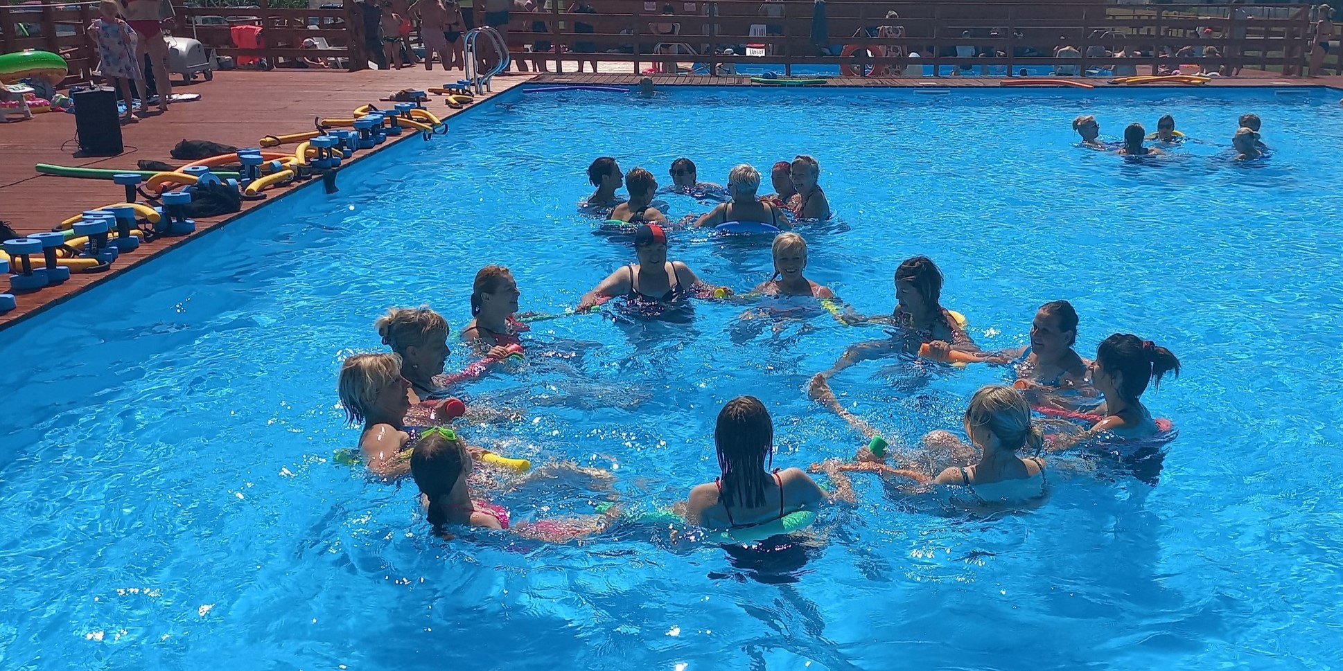 Zdjęcie przedstawia grupę osób wykonującą ćwiczenia fizyczne w basenie.