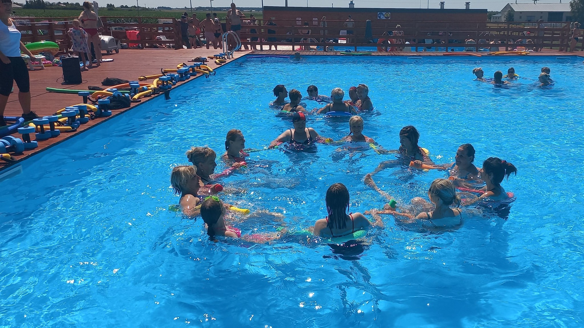 Zdjęcie przedstawia grupę osób wykonującą ćwiczenia fizyczne w basenie.