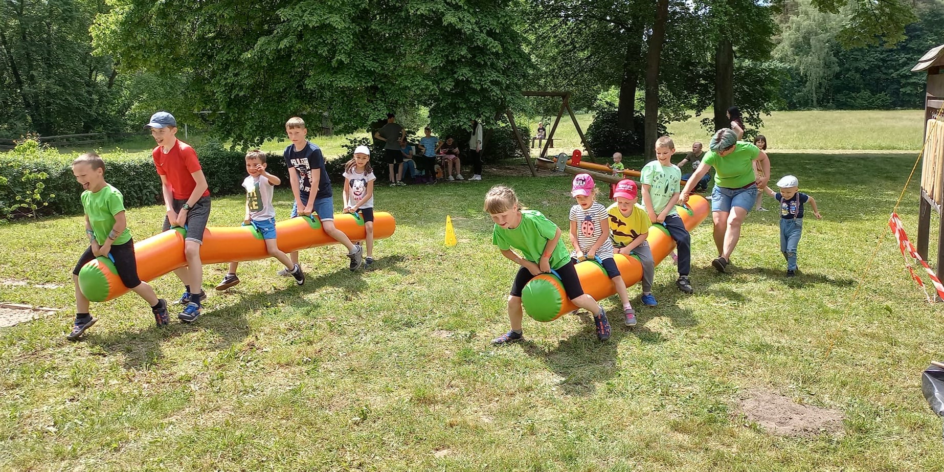 Zdjęcie przedstawia 2 grupy dzieci rywalizujących ze sobą w wyścigu sprawnościowym